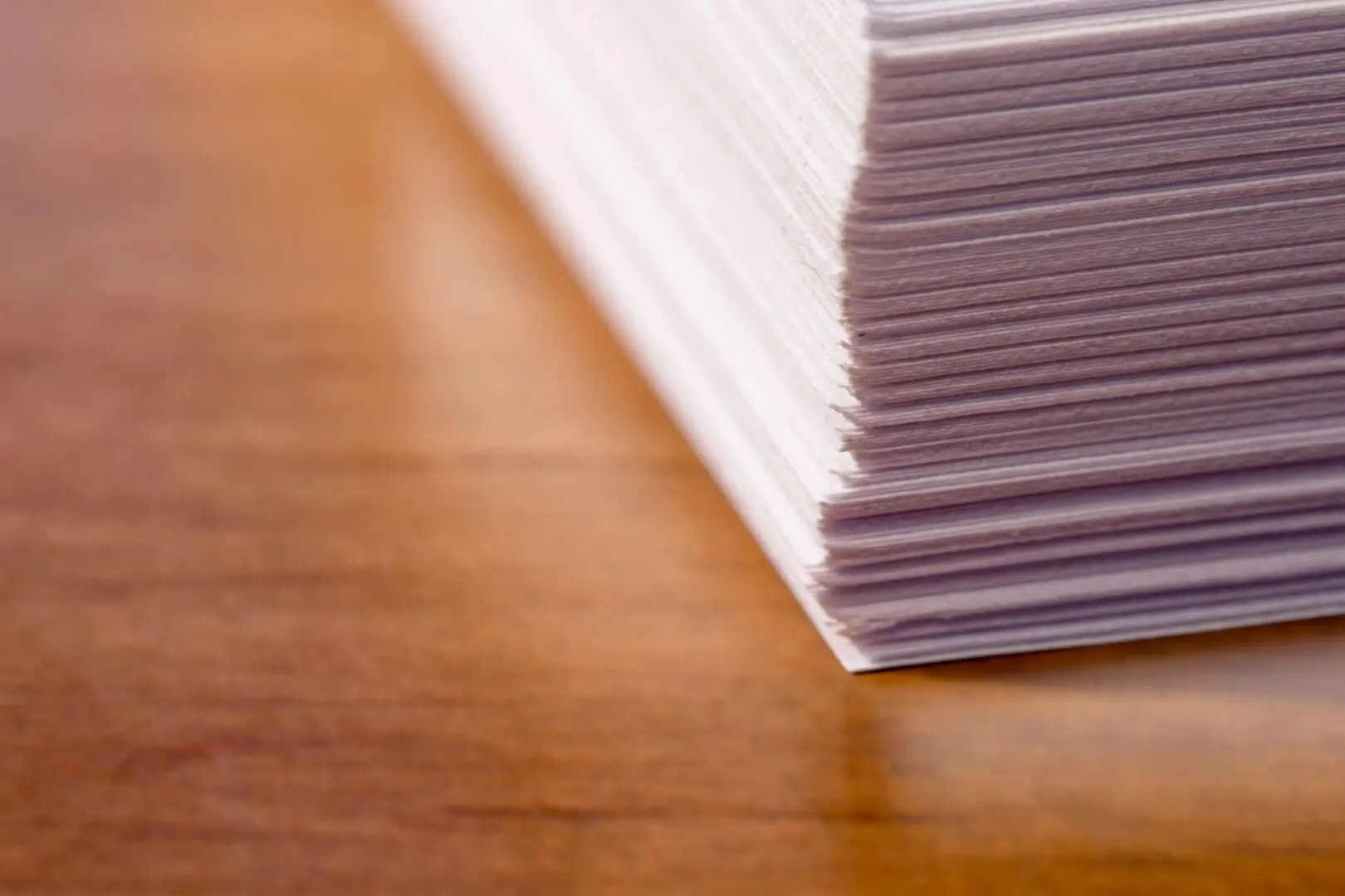 A stack of papers on top of a wooden table.
